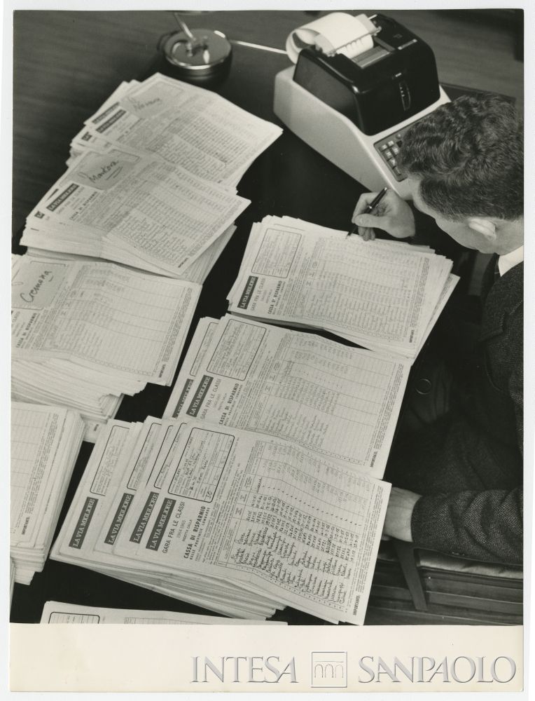 Impiegato Cariplo dell'Ufficio Propaganda esamina i moduli cartacei della "Gara fra le classi" per decretare la classe e l'alunno più risparmiatore, aprile 1965 (Publifoto)