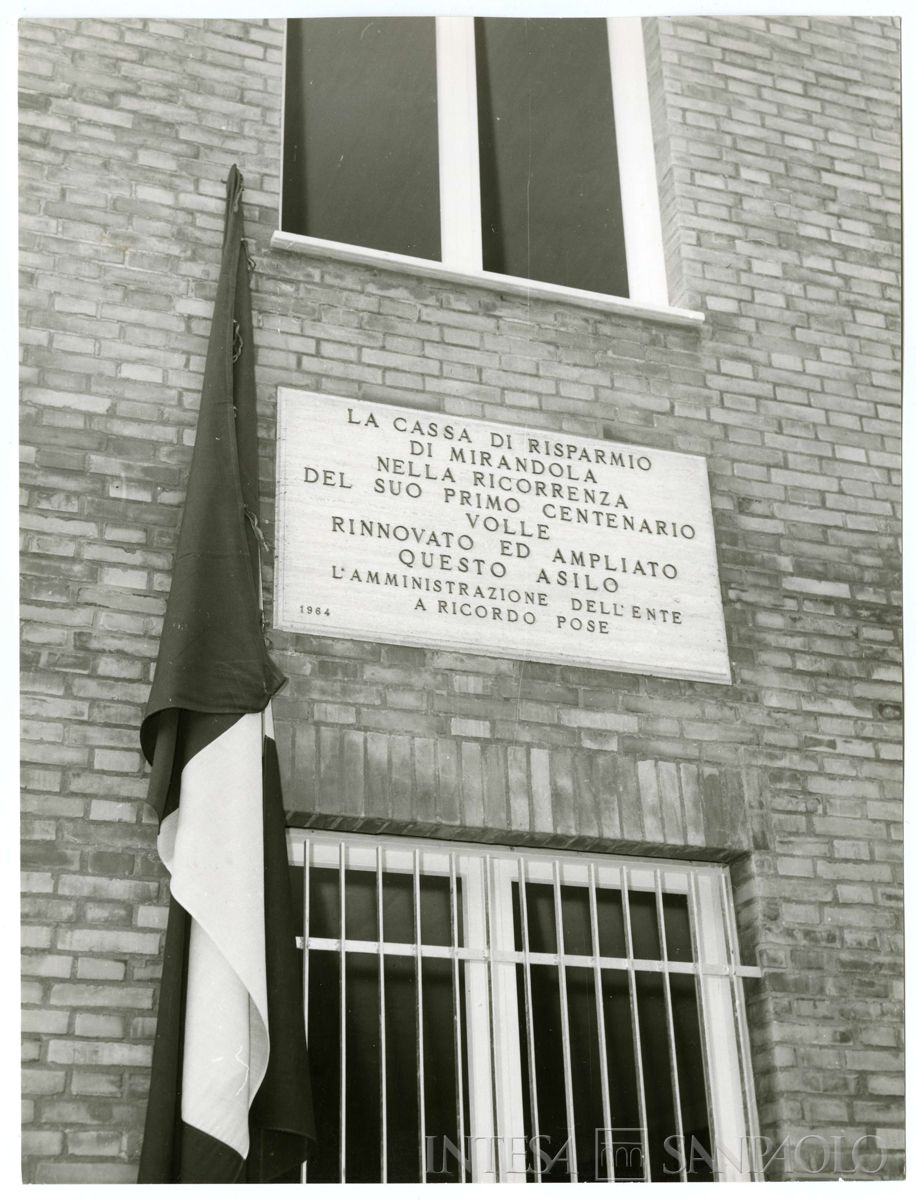 Particolare della targa commemorativa affissa sul nuovo padiglione dell'Asilo Infantile di Mirandola inaugurata in occasione delle celebrazioni del centenario della Cassa di Risparmio di Mirandola, 19 ottobre 1964 (foto G. Trentini)