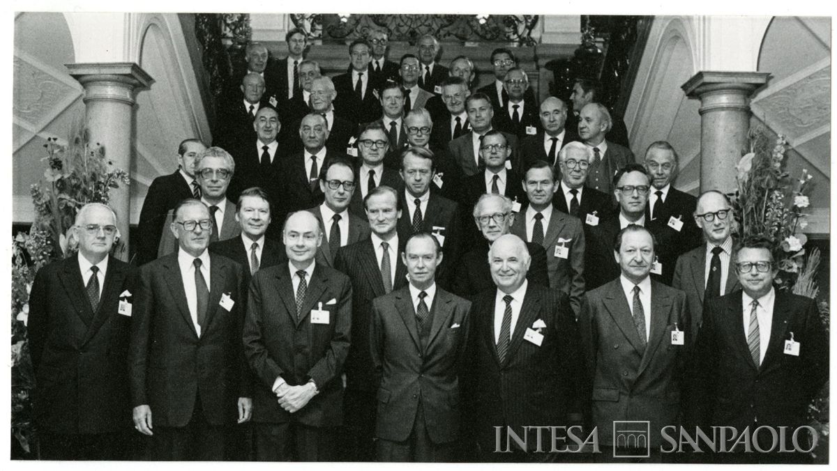 Ritratto di gruppo dei partecipanti della LXIV sessione dell'Institut International d'Études Bancaires: Antonio Monti, amministratore delegato della BCI è a sinistra, accanto alla colonna, parzialmente coperto da un altro partecipante, 6 maggio 1983 (fotografo sconosciuto)