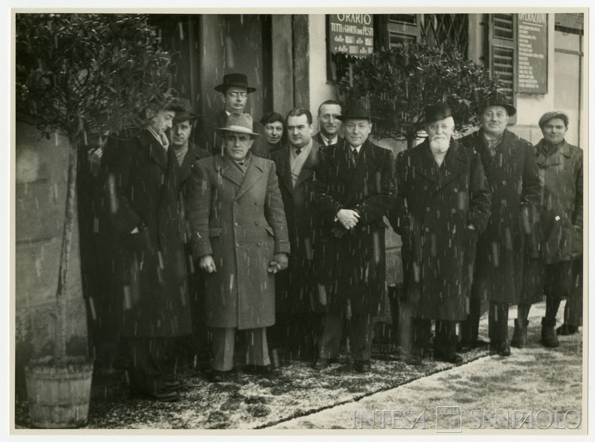 Partecipanti all'esterno della filiale Cariplo di Cinisello, mentre nevica, il giorno dell'inaugurazione; quarto da destra il vice presidente Cesare Chiodi e quarto da sinistra, il più alto di tutti, l'ingegnere Capo del Servizio Tecnico Sandro Candiani, 8 febbraio 1947 (Ubaldo Vaini)