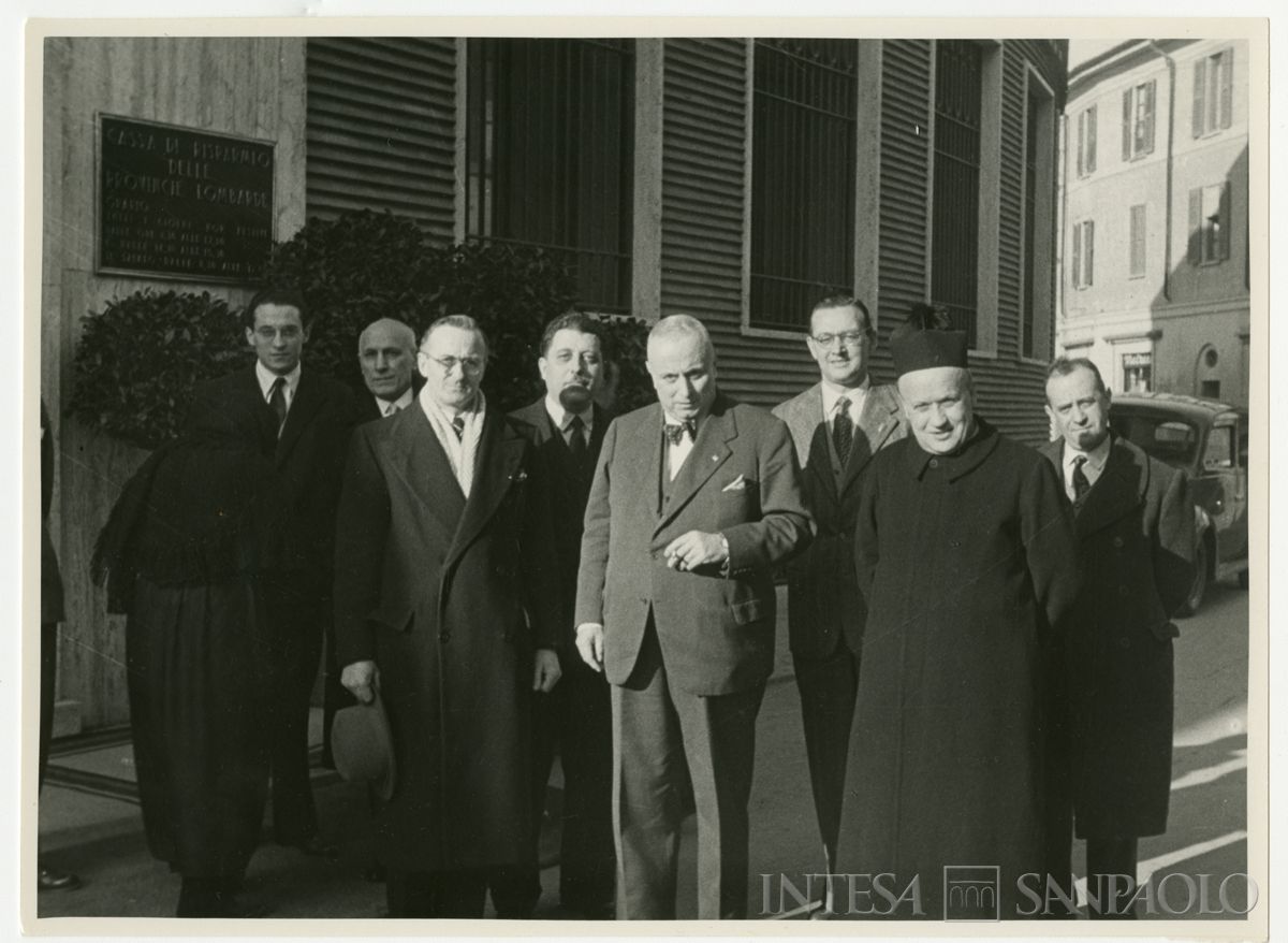 Foto di gruppo all'inaugurazione della filiale Cariplo di Melzo, a sinistra sullo sfondo; con papillon, accanto al parroco, il presidente Stefano Jacini, gennaio 1950 (Angelo Vitali)