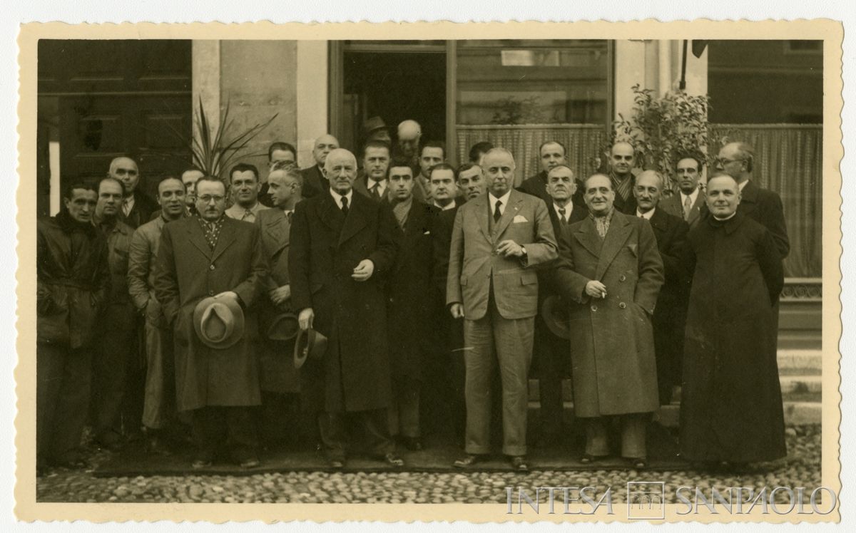 Foto di gruppo all'esterno della filiale Cariplo di S. Benedetto Po il giorno dell'inaugurazione; in prima fila, terzo da destra, il presidente Stefano Jacini; in seconda fila, secondo da destra, il direttore generale Gian Luigi Dones, in ultima, secondo da destra, Bruno Minoja, 27 dicembre 1946 (A. Bonora)