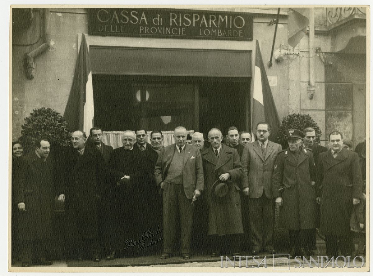 Foto di gruppo all'esterno della filiale Cariplo di Vescovato il giorno dell'inaugurazione; il secondo da sinistra è Bruno Minoja, il quarto è l'ingegnere capo del Servizio Tecnico Sandro Candiani e l'ottavo il presidente Stefano Jacini, 9 gennaio 1947 (Olindo Bini)