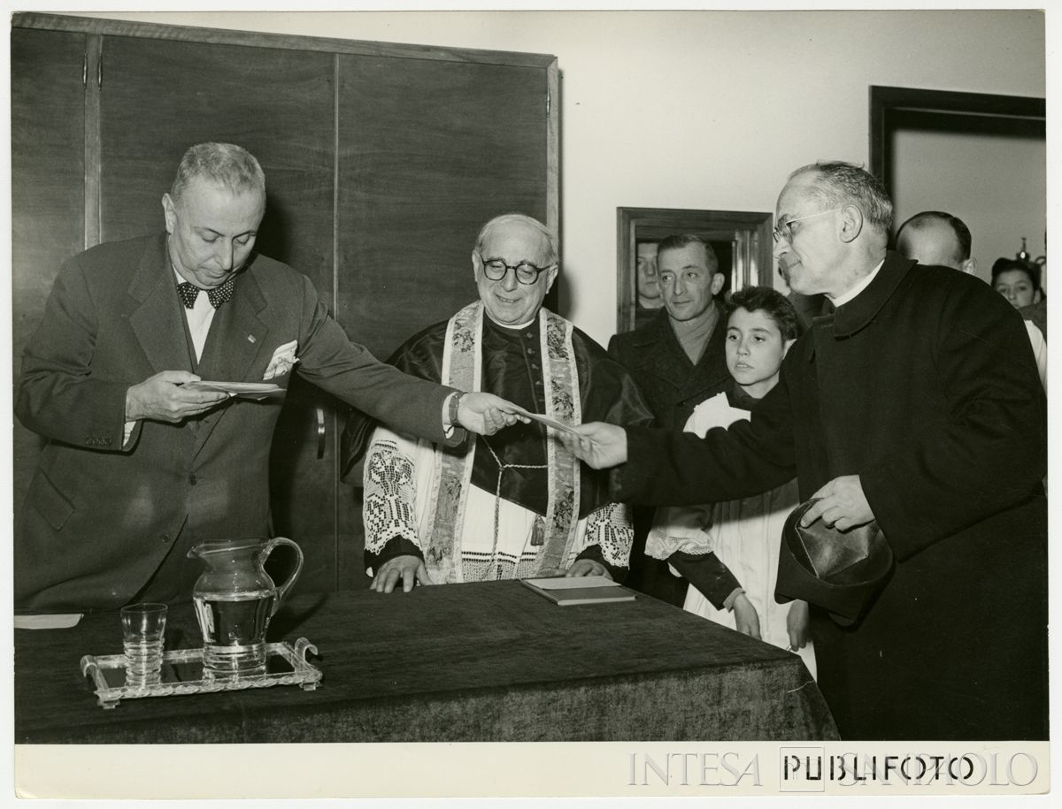Consegna di elargizioni benefiche al parroco da parte del presidente della Cariplo Stefano Jacini durante l'inaugurazione della filiale di Paderno Dugnano, 5 dicembre 1950 (Publifoto)