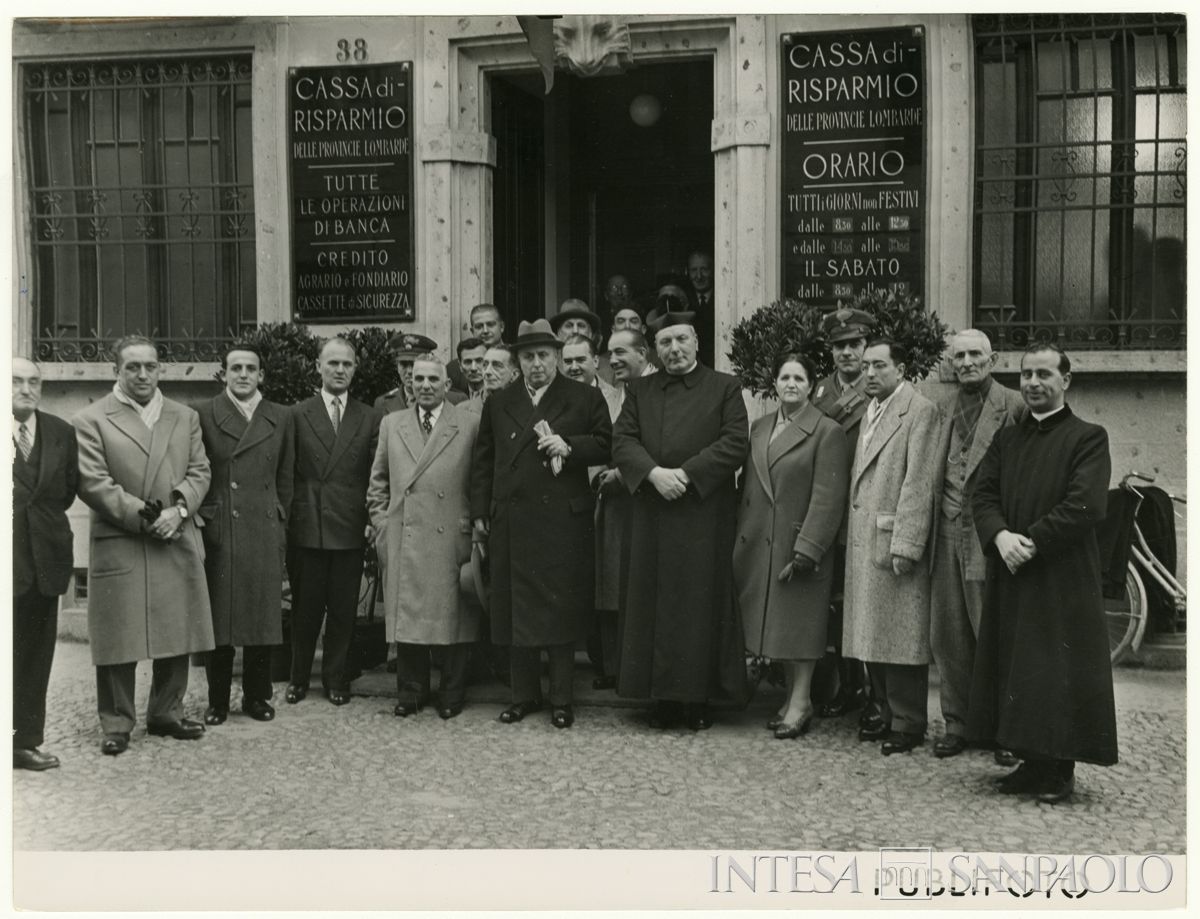 Foto di gruppo all'esterno della filiale Cariplo di Pieve del Cairo, il giorno dell'inaugurazione; al centro, con i guanti in mano, il presidente Stefano Jacini, 9 dicembre 1950 (Publifoto)