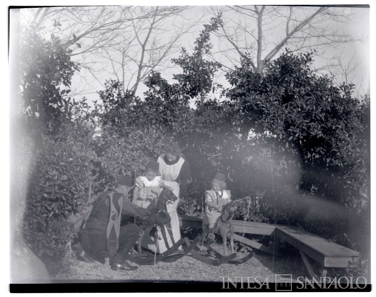 Nogara Johnny e Josy sui cavalli a dondolo, con la madre Ester e un cavas, 1903  - 1904 (Bernardino Nogara)