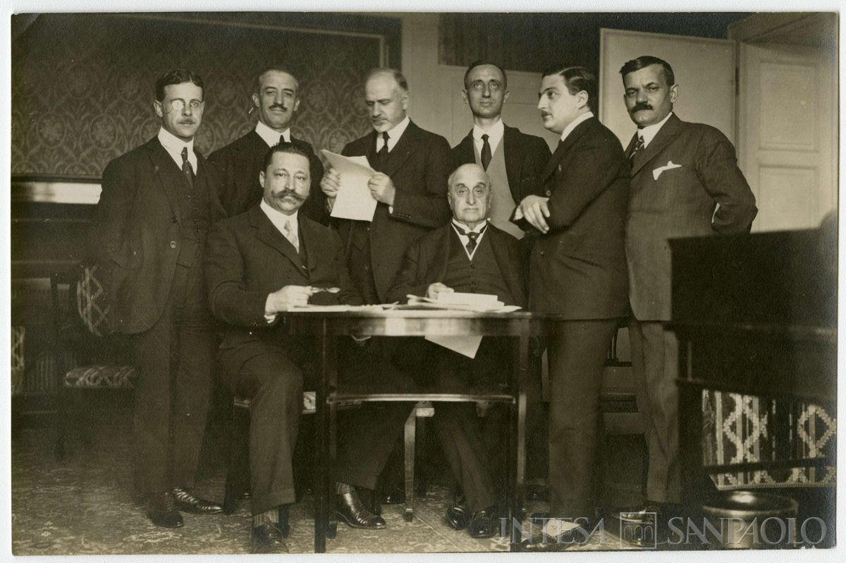 Conferenza internazionale di Losanna per la pace con la Turchia: partecipanti ritratti seduti a un tavolo; il secondo in piedi da destra [Raffaele Guarriglia], il quarto in piedi Bernardino Nogara, seduto a destra Camillo Garroni, 1922 - 1923 (fotografo sconosciuto)