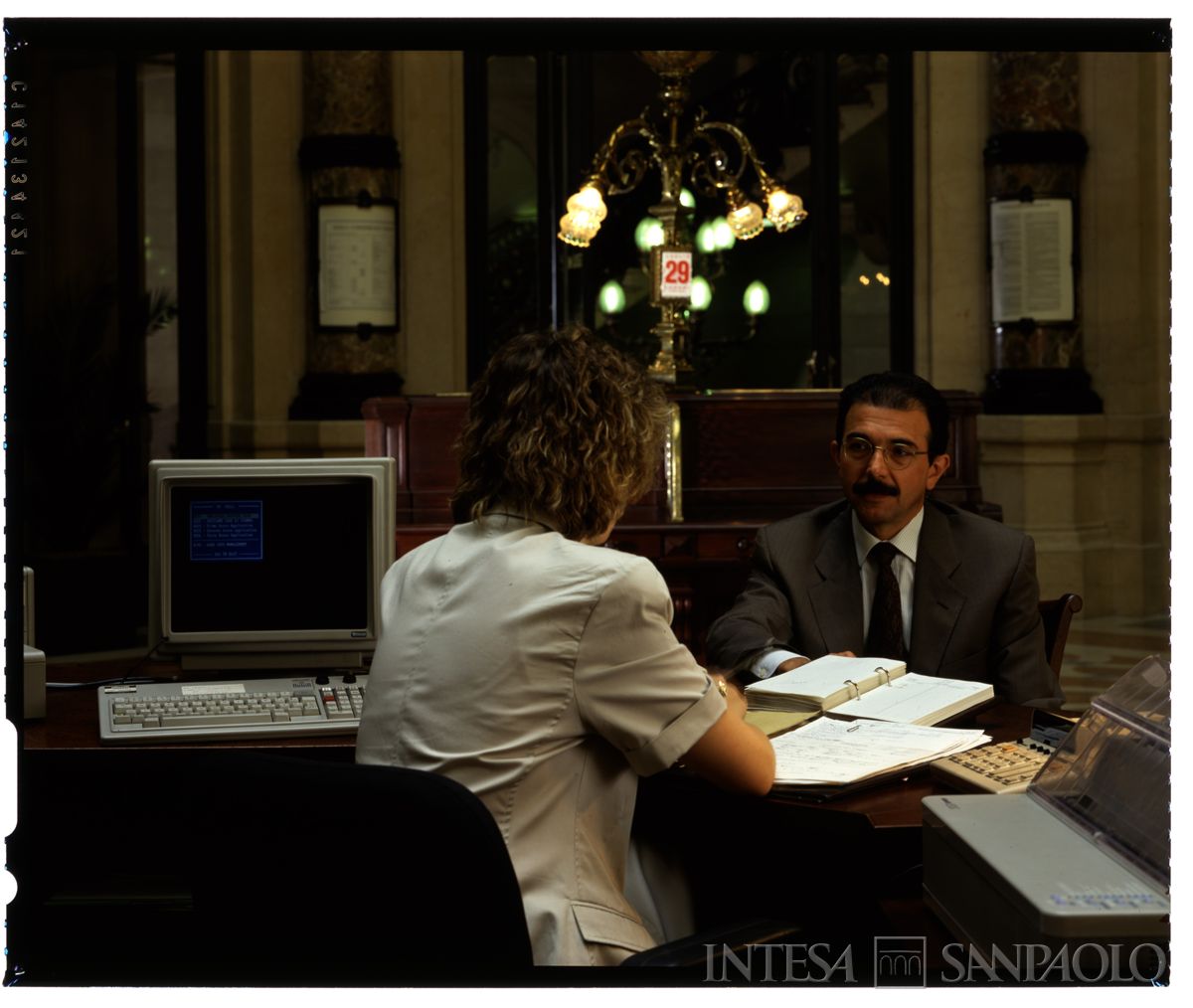 Palazzo di piazza della Scala 6, salone A: dettaglio del bancone centrale con cliente e personale al lavoro, anni Novanta (foto di Immagine S.a.s)