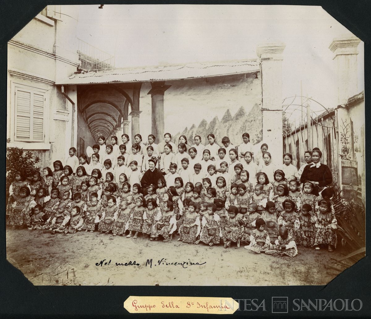Istituto Canossiano italiano a Han-Kow (Cina), Sant'Infanzia: ritratto di gruppo nel cortile delle bambine e ragazze, con al centro M. Vincenzina, 1900 (fotografo sconosciuto)