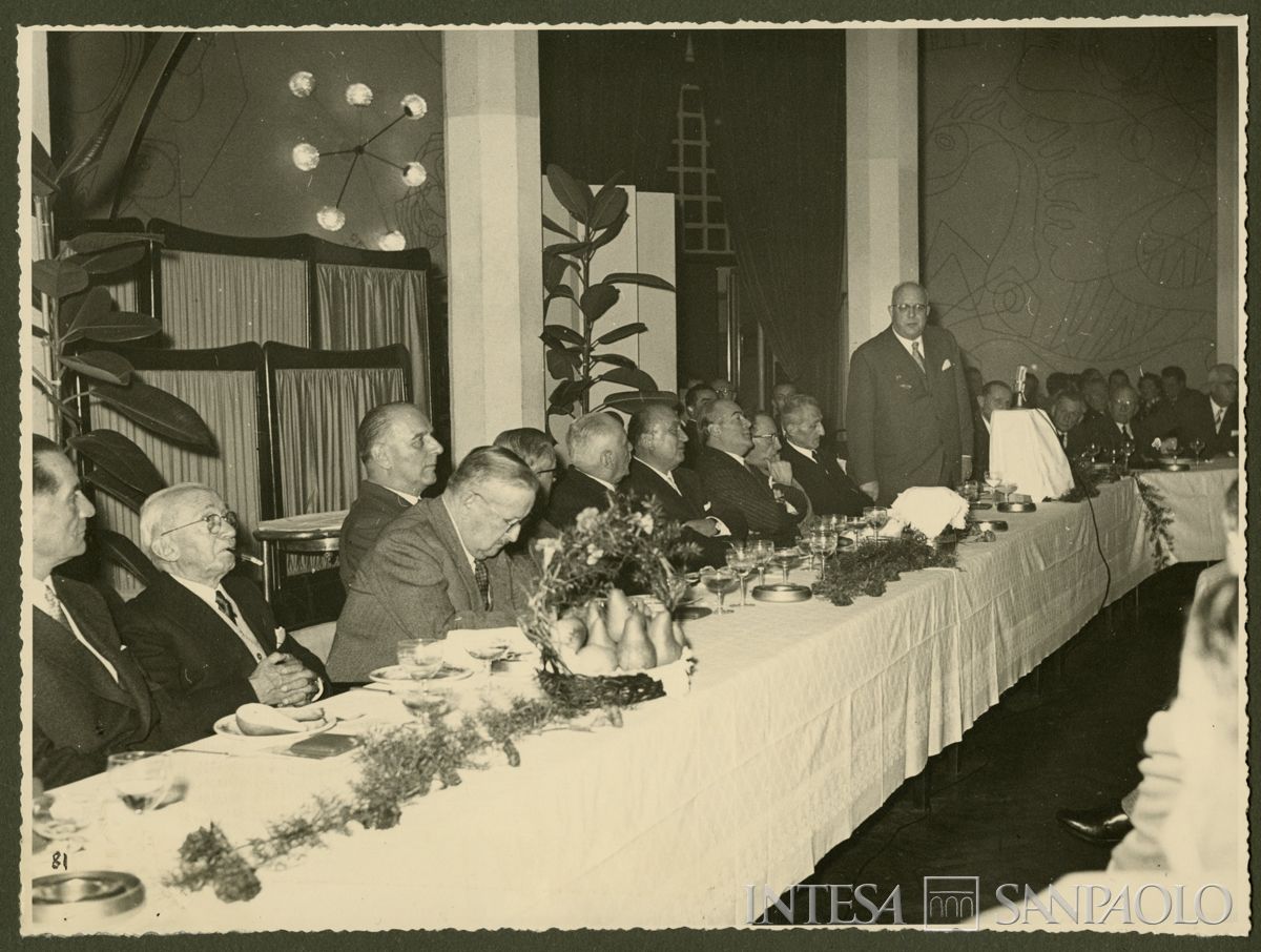 Luigi Brusati mentre tiene il discorso al banchetto promosso dal personale del Banco Ambrosiano per il sessantesimo di fondazione, Milano, 18 novembre 1956 (fotografo sconosciuto)