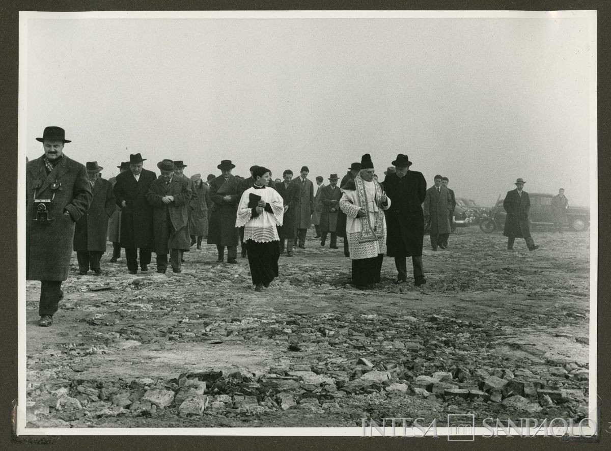 Il parroco don Guido Cristini a colloquio con il presidente del Banco Ambrosiano Tommaso Gallarati Scotti nell'area di costruzione delle case del piano INA-CASA, Milano, 12 agosto 1956 (fotografo sconosciuto)