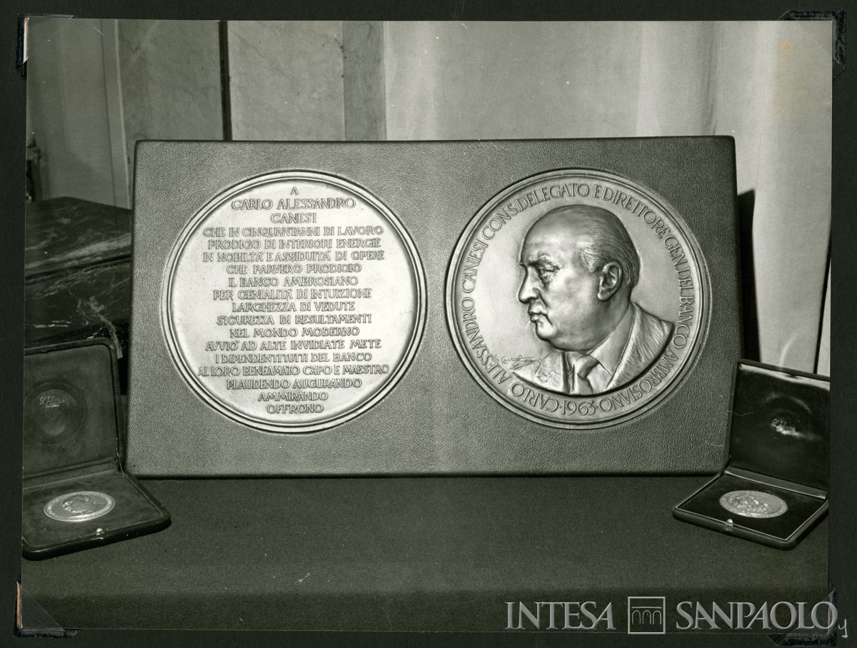 Targa recante le facce ingrandite della medaglia realizzata per i cinquantanni di lavoro di Carlo Alessandro Canesi; accanto due cofanetti con le medaglie realizzate dallo scultore Giannino Castiglioni, 7 dicembre 1963 (Publifoto)