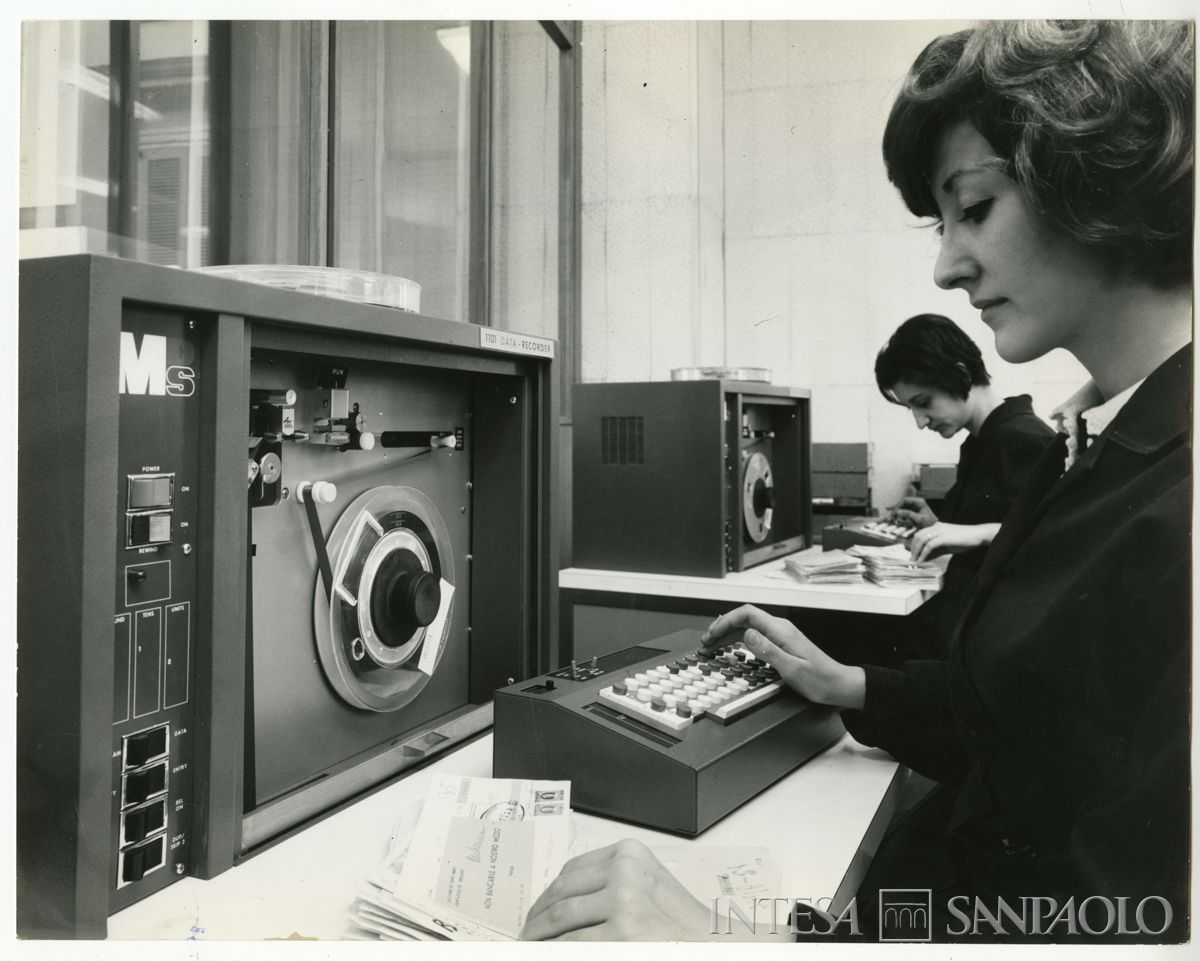 Cariplo, Centro Elettronico (C.E.) di Milano, Via Verdi 11: personale femminile al lavoro presso le postazioni con macchinari MDS per la registrazione di dati su nastri magnetici, 1969 (foto di Elle2)