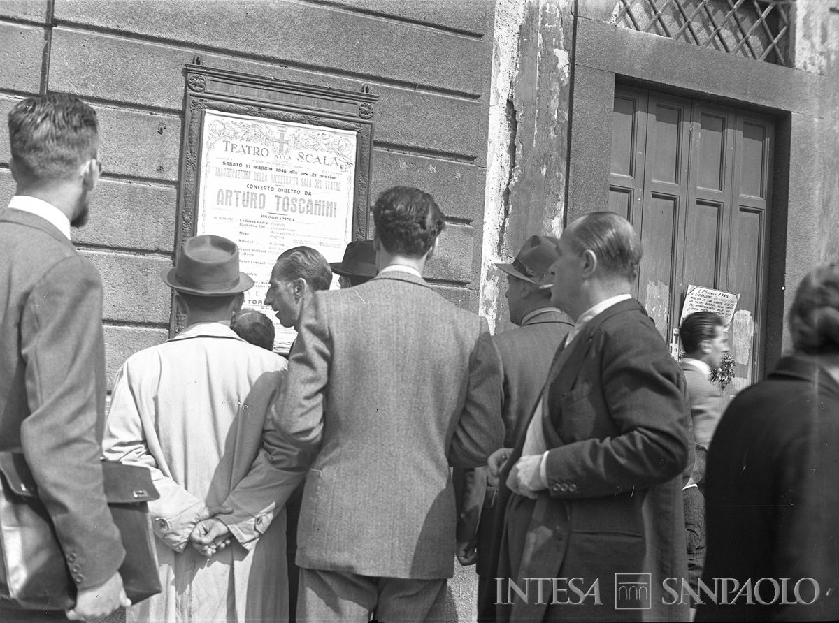 Un gruppo di persone legge il manifesto che annuncia il concerto di riapertura della Scala diretto da Toscanini, 10 maggio 1946 (Publifoto)
