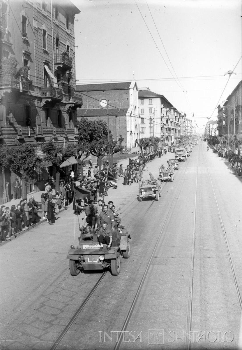 Ingresso a Milano delle truppe americane: la colonna è guidata da una autoblindo condotto dai partigiani su cui è incollata la scritta: "Evviva il Partito Comunista", 2 maggio 1945. Fotografia di Publifoto