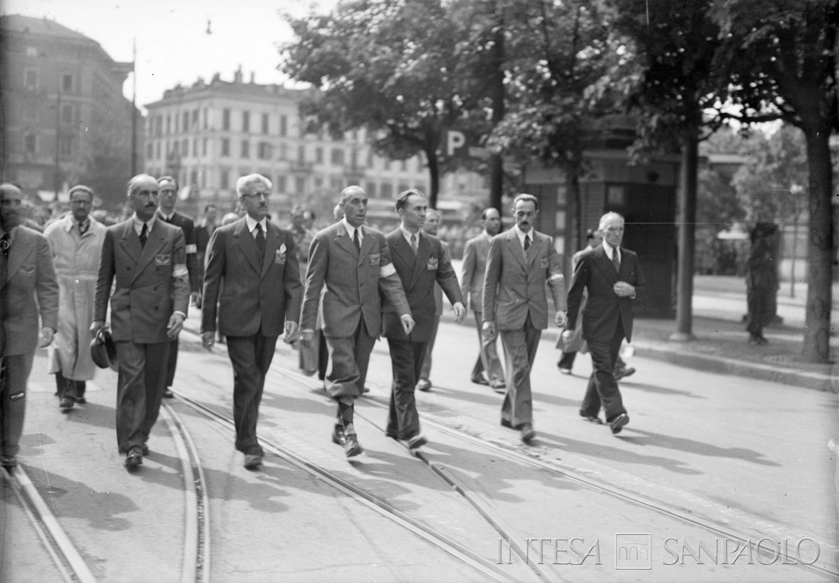 Sfilata in piazza del Duomo a Milano delle formazioni del C.V.L. (Corpo volontari della libertà): da sinistra, Mario Argenton, Giovan Battista Stucchi, Ferruccio Parri, il generale Raffaele Cadorna, Luigi Longo, Enrico Mattei e Fermo Solari, 6 maggio 1945. Fotografia di Publifoto
