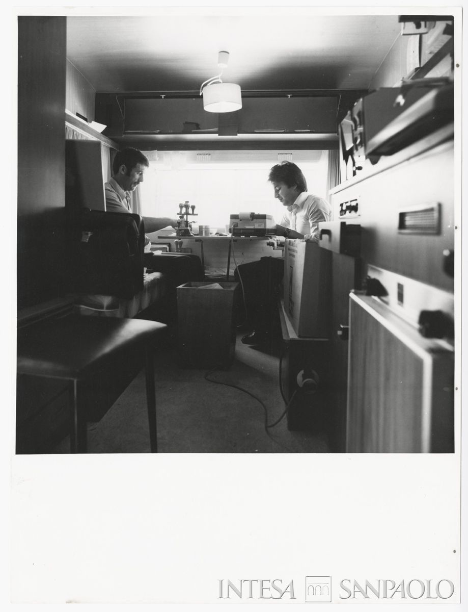 Impiegati al lavoro all'interno della roulotte adibita a sportello provvisorio della Banca Cattolica del Veneto a Maiano, post 6 maggio 1976. . Archivio Storico Intesa Sanpaolo, sezione fotografica BCV