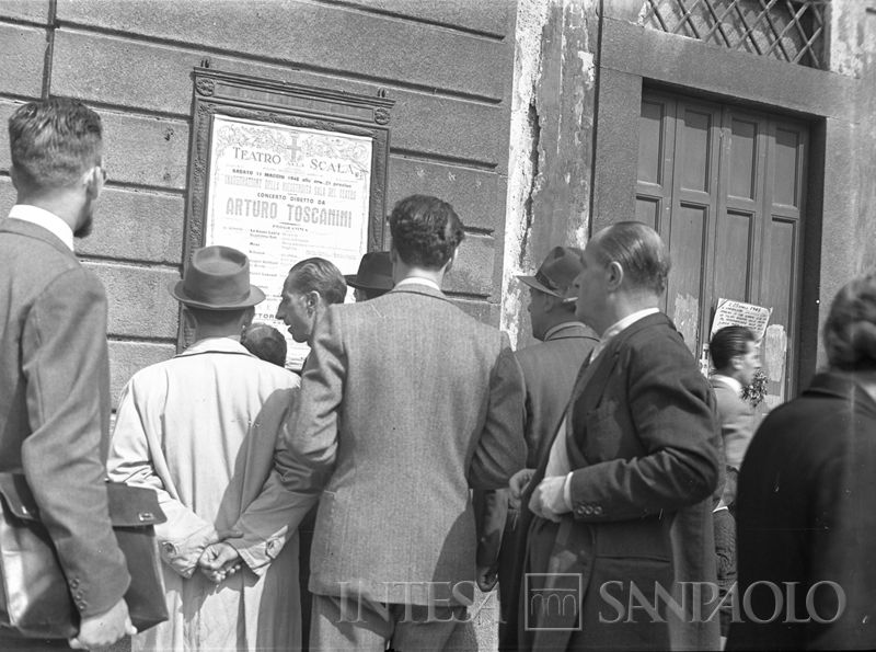 Un gruppo di persone legge il manifesto che annuncia il concerto di riapertura della Scala diretto da Toscanini, 10 maggio 1946 (Publifoto)