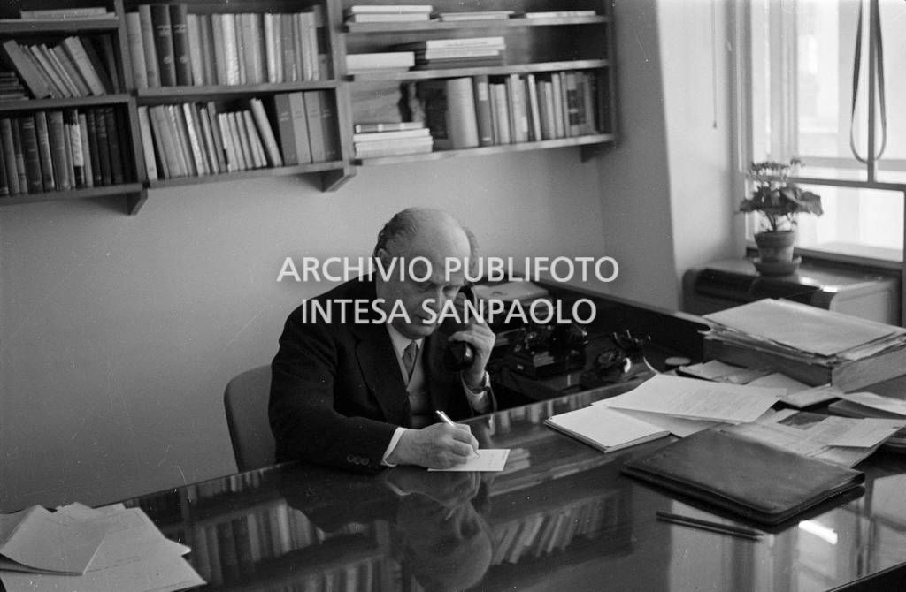 Adriano Olivetti seduto alla scrivania con la cornetta del telefono in mano<br>453483