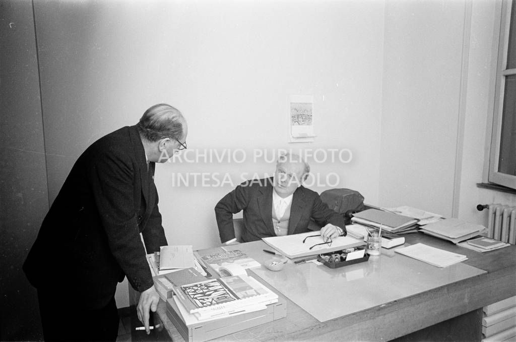Adriano Olivetti, seduto alla scrivania, discorre con un collaboratore<br>453491