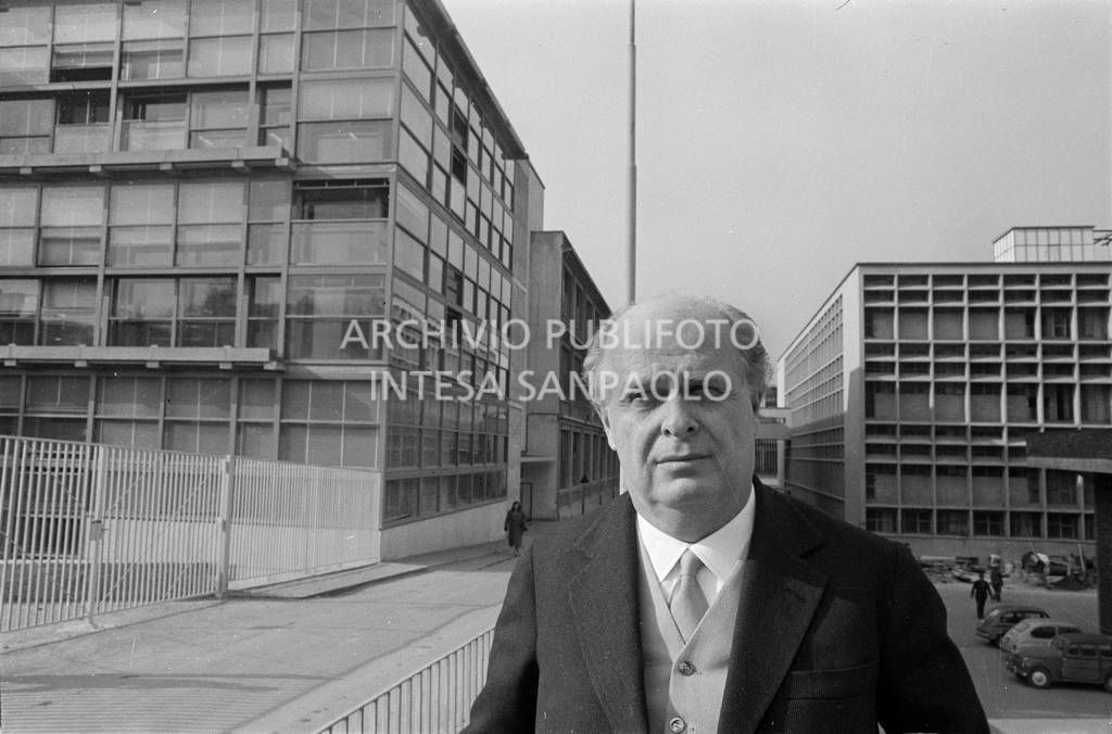 Adriano Olivetti ritratto con gli edifici industriali alle spalle<br>453494