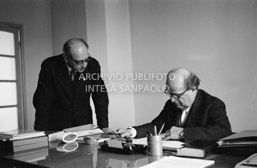Adriano Olivetti seduto alla scrivania; alla sua destra un collaboratore<br>453511