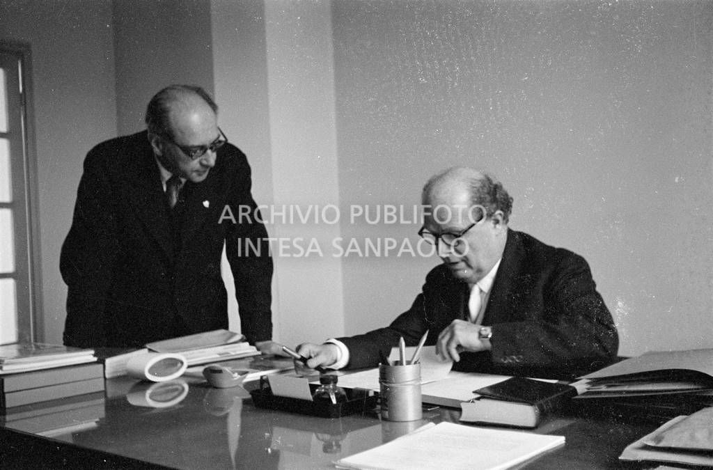 Adriano Olivetti seduto alla scrivania; alla sua destra un collaboratore<br>453512