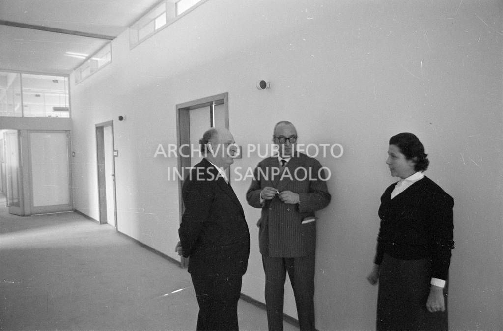 Adriano Olivetti in un corridoio discorre con un uomo e una donna<br>453524