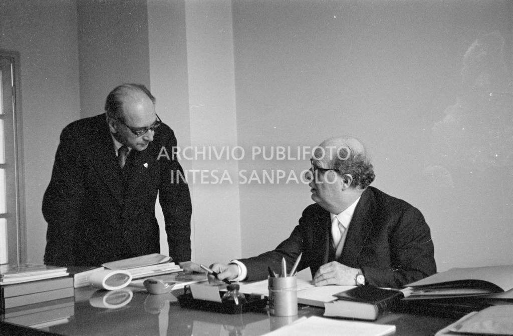 Adriano Olivetti, seduto alla scrivania, discorre con un collaboratore<br>453525