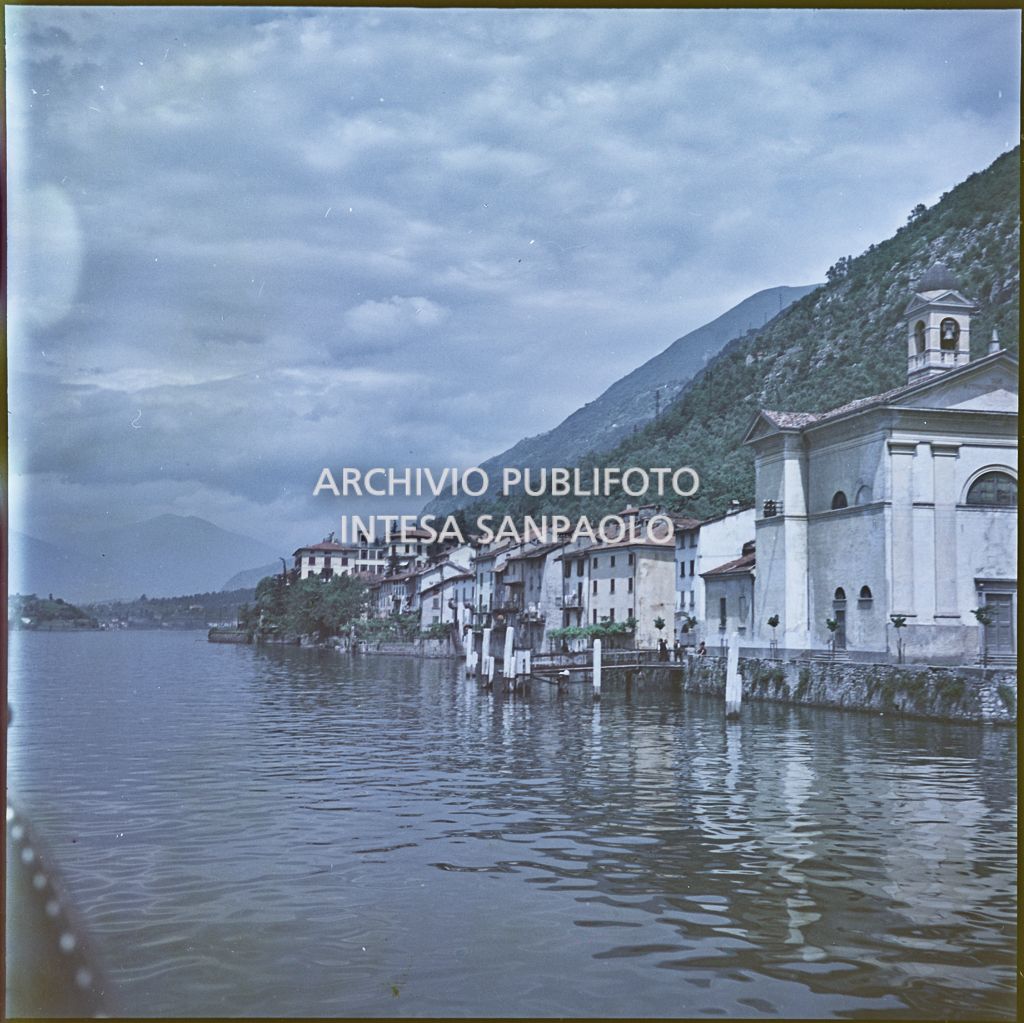 Lungolago con abitazioni e chiesa visti da un'imbarcazione<br>342