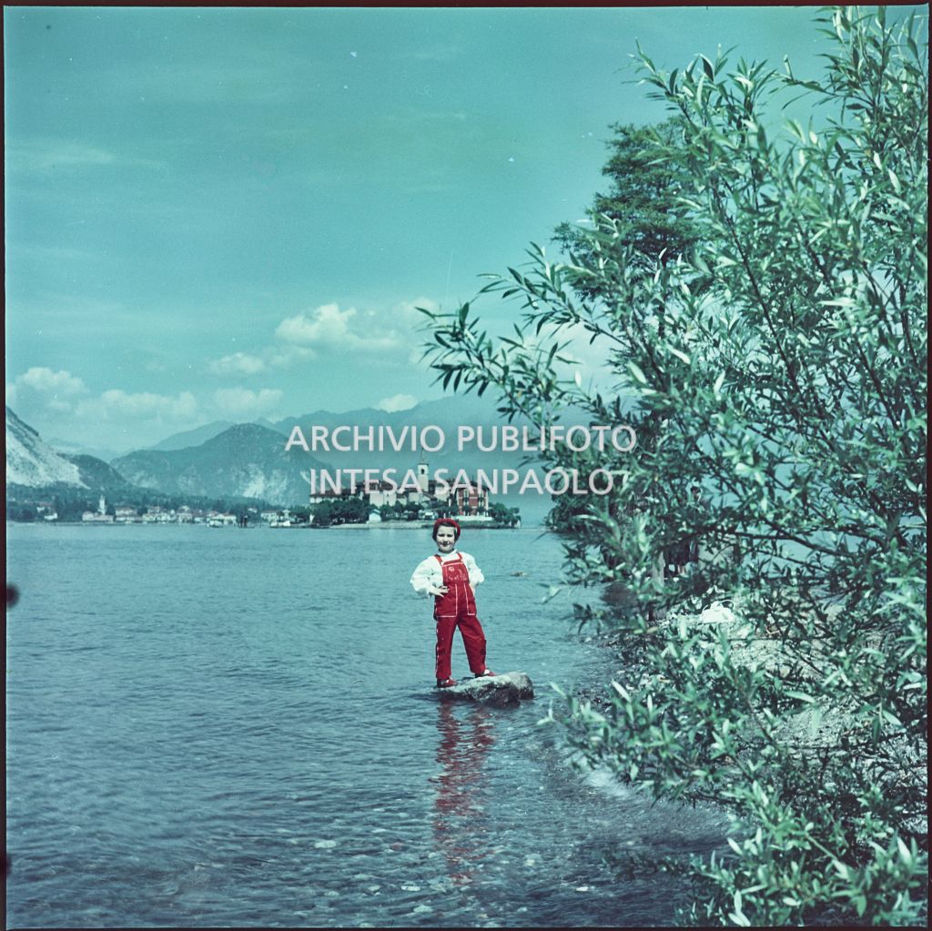 Bambina in posa su uno scoglio in riva al lago Maggiore. Sullo sfondo è visibile l'Isola dei Pescatori<br>347