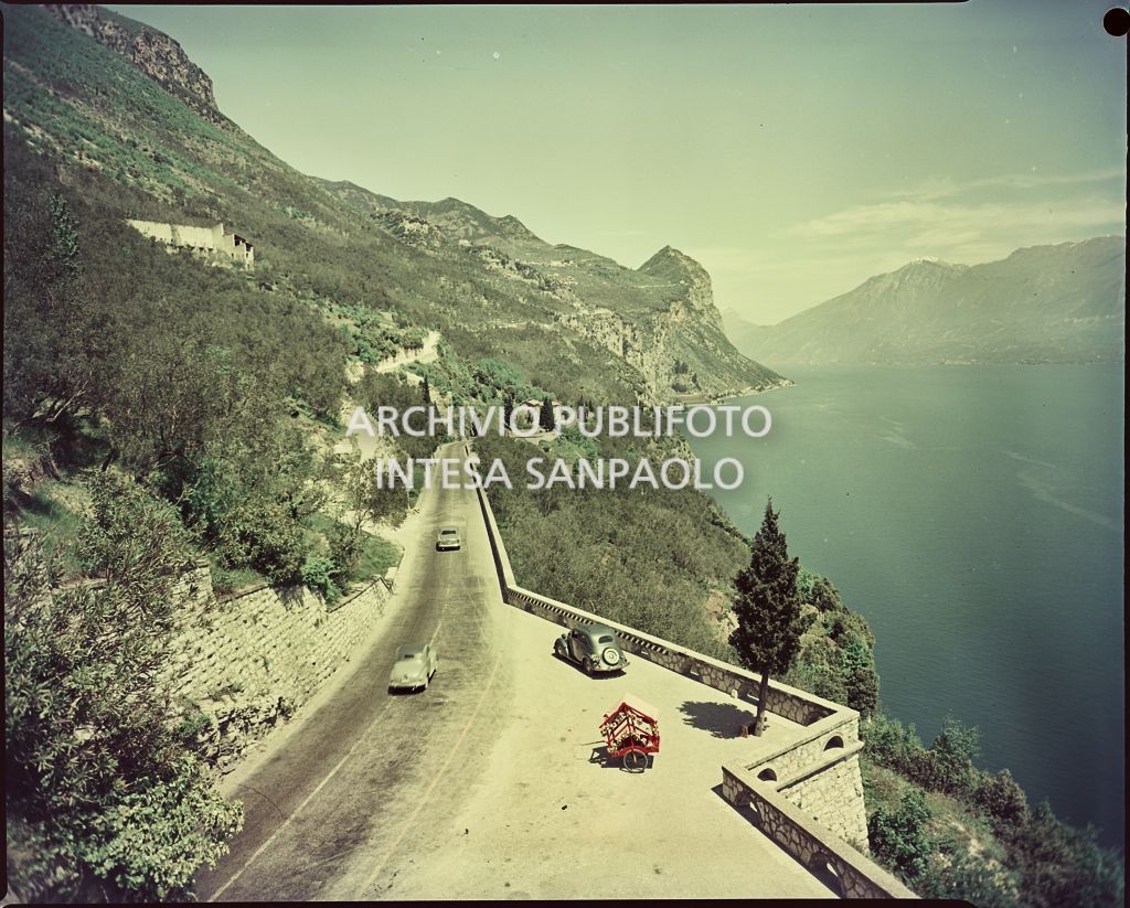 Vista di una strada con spiazzo per la sosta sul fianco di una montagna in riva al lago<br>754
