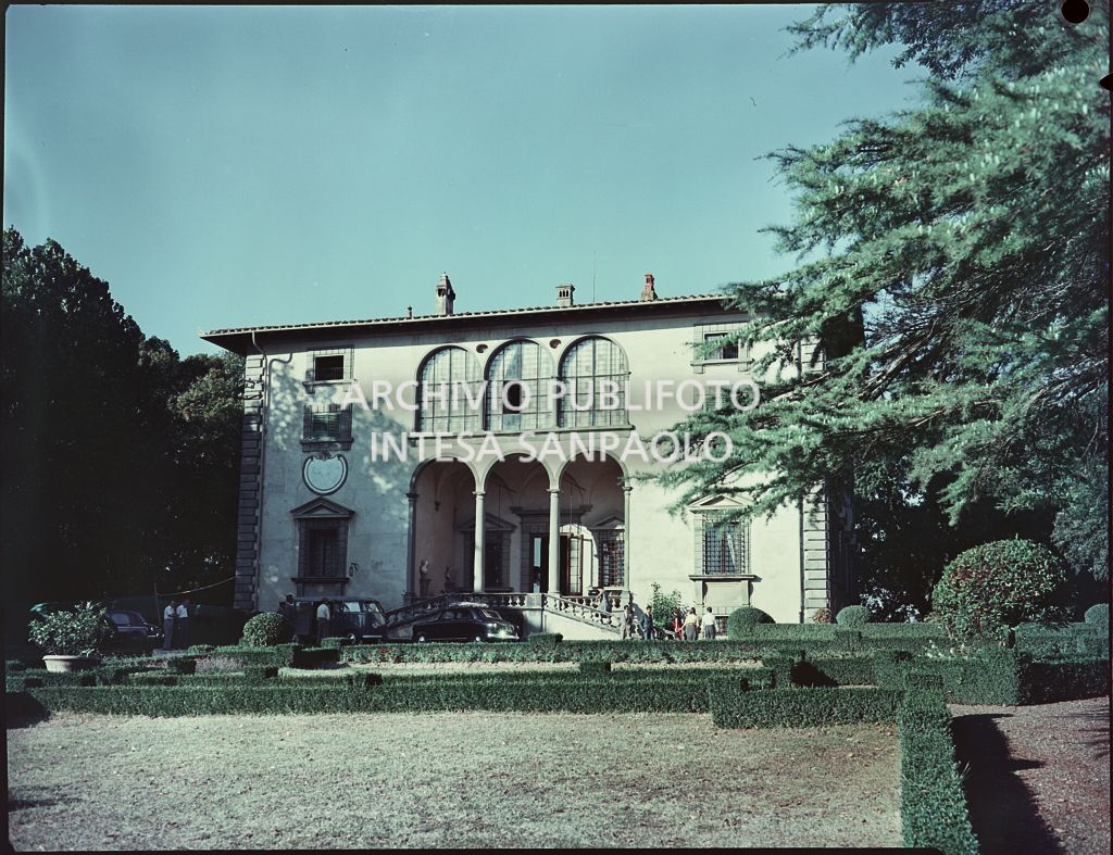 Veduta esterna della villa e del giardino; visibili alcune persone ed automobili parcheggiate<br>820