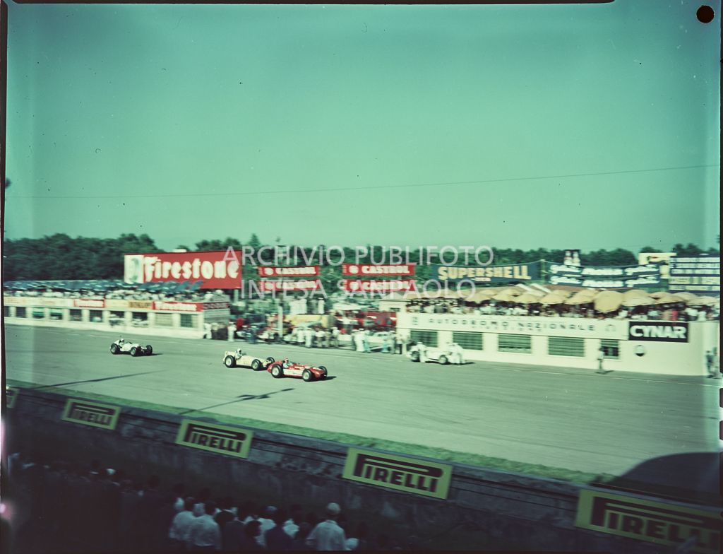 Vista dagli spalti della pista e delle automobili. Sono visibili le seguenti insegne pubblicitarie: Firestone, Castrol, Supershell, Motta, Cynar, Pirelli<br>1540