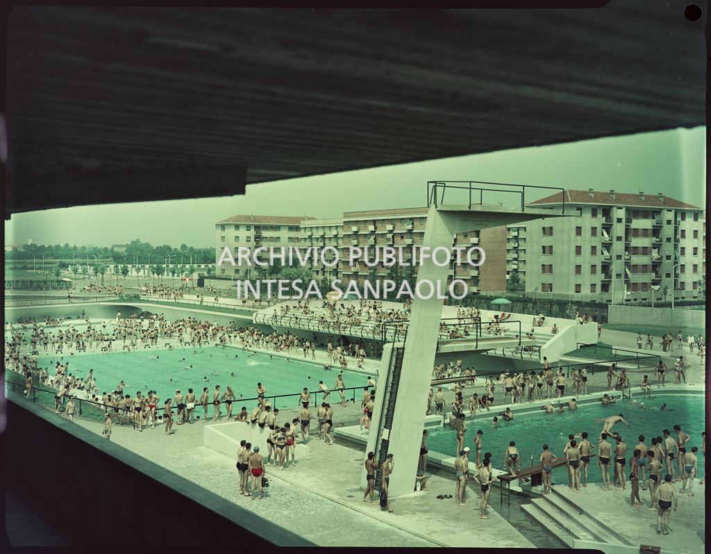 Piscine con bagnanti viste dall'alto. In primo piano una serie di trampolini, mentre sullo sfondo sono visibili dei palazzi<br>1589