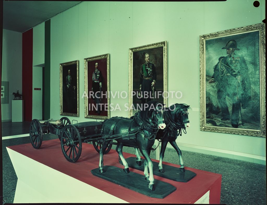 Sala espositiva delle mostra "Il Cinquantanove" a Palazzo Reale di Milano con modellino due un carro con cannone trainato da due cavalli e ritratti sulla parete<br>2320