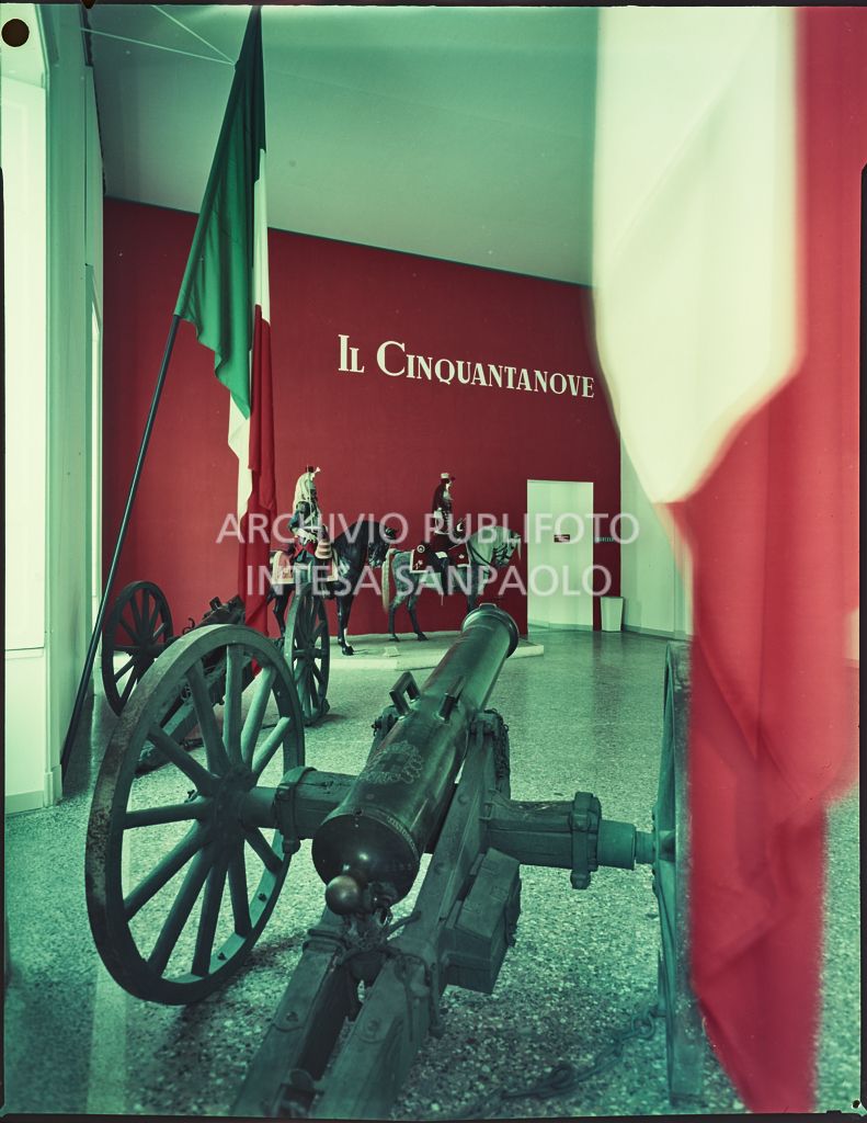 Ingresso della mostra "Il Cinquantanove" a Palazzo Reale di Milano con due cannoni, le bandiere italiane e le riproduzioni di due cavalieri con le insegne di Napoleone III<br>2321