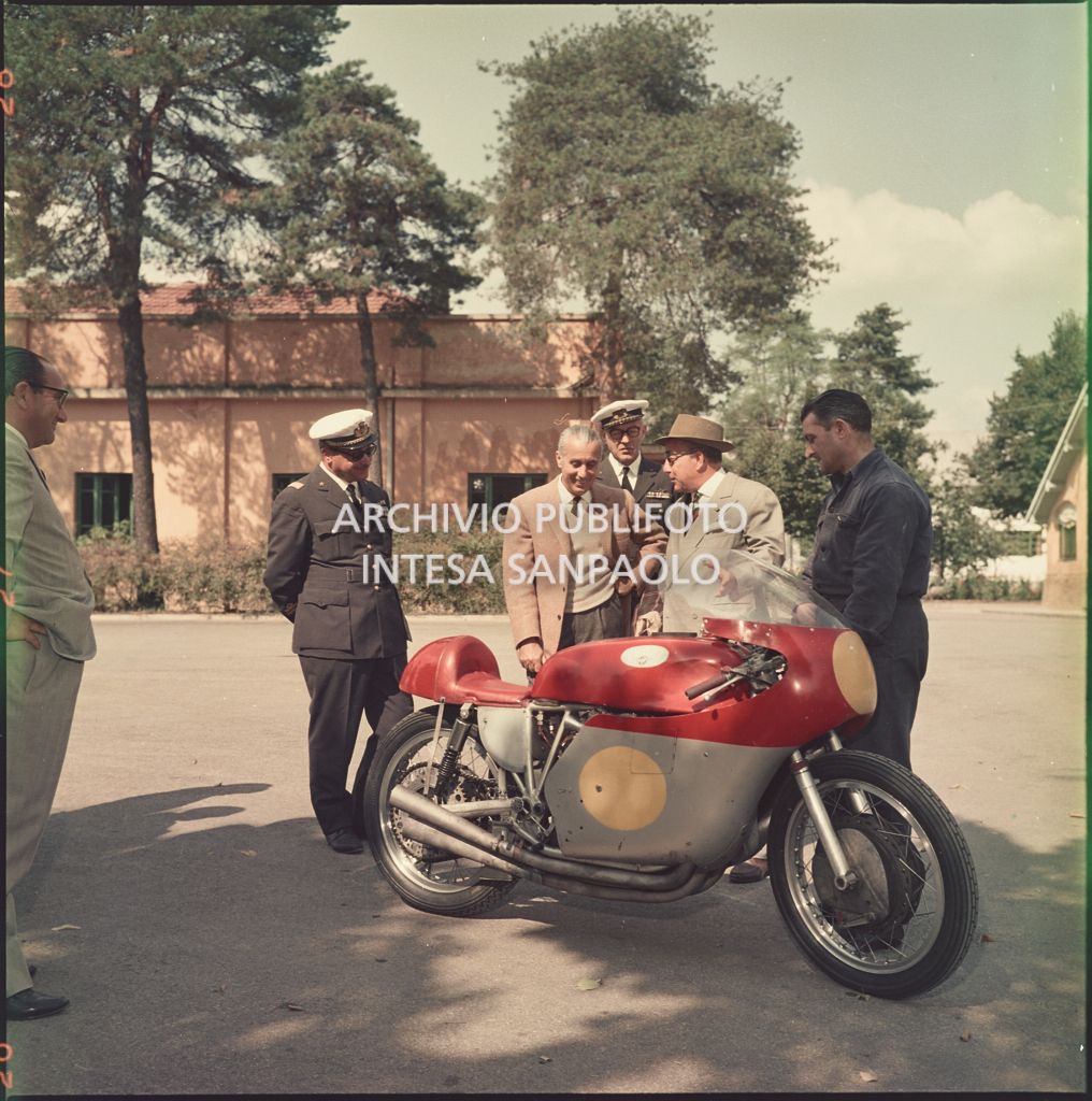 Domenico Agusta con un meccanico mostrano la moto da corsa MV Agusta ad un uomo non identificato e due ufficiali dell'aeronautica<br>5415