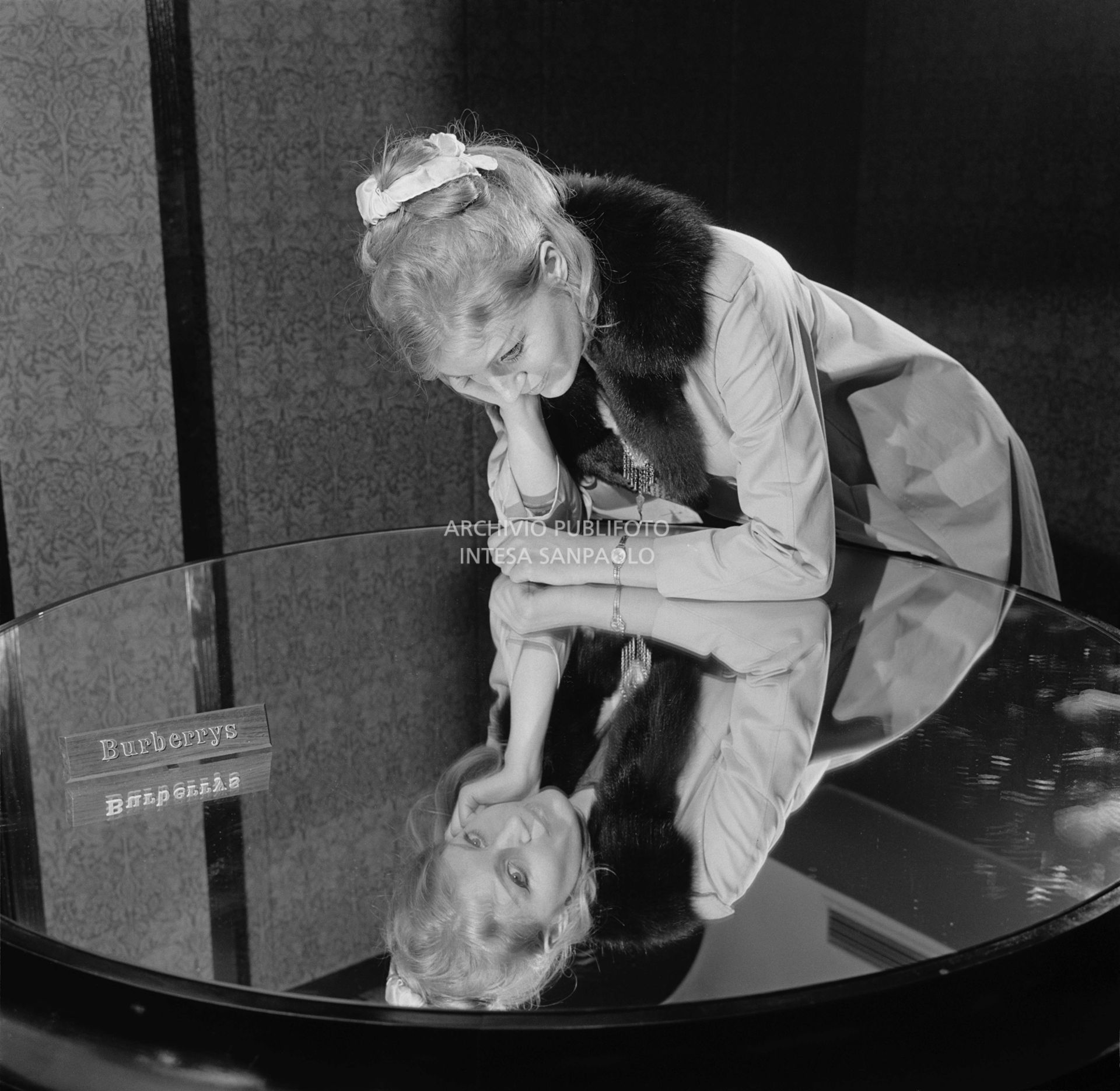 Anna German, con indosso un trench con l'interno in pelliccia, si specchia in un tavolino al negozio Burberrys'<br>727771/42