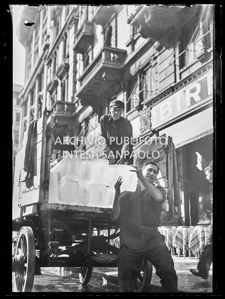 Due uomini scaricano blocchi di ghiaccio da un carro