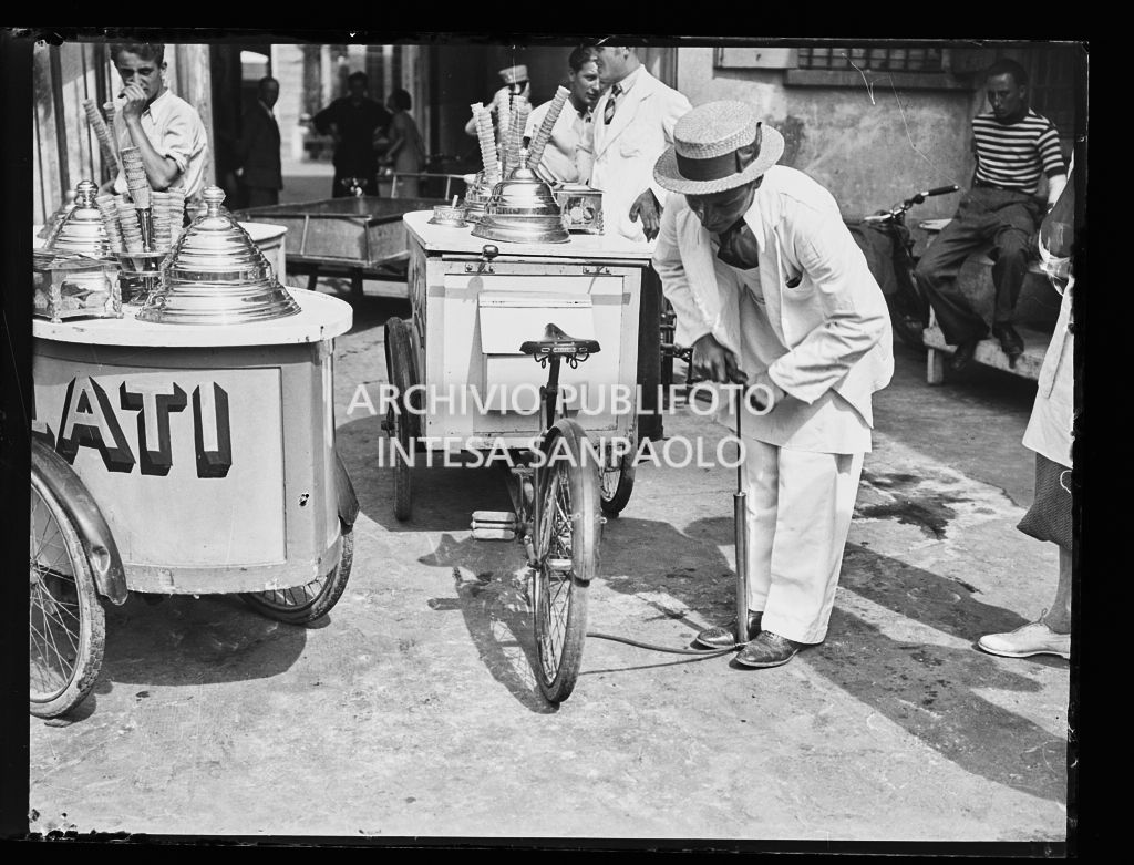 Un gelataio ambulante gonfia la ruota della bicicletta con carretto