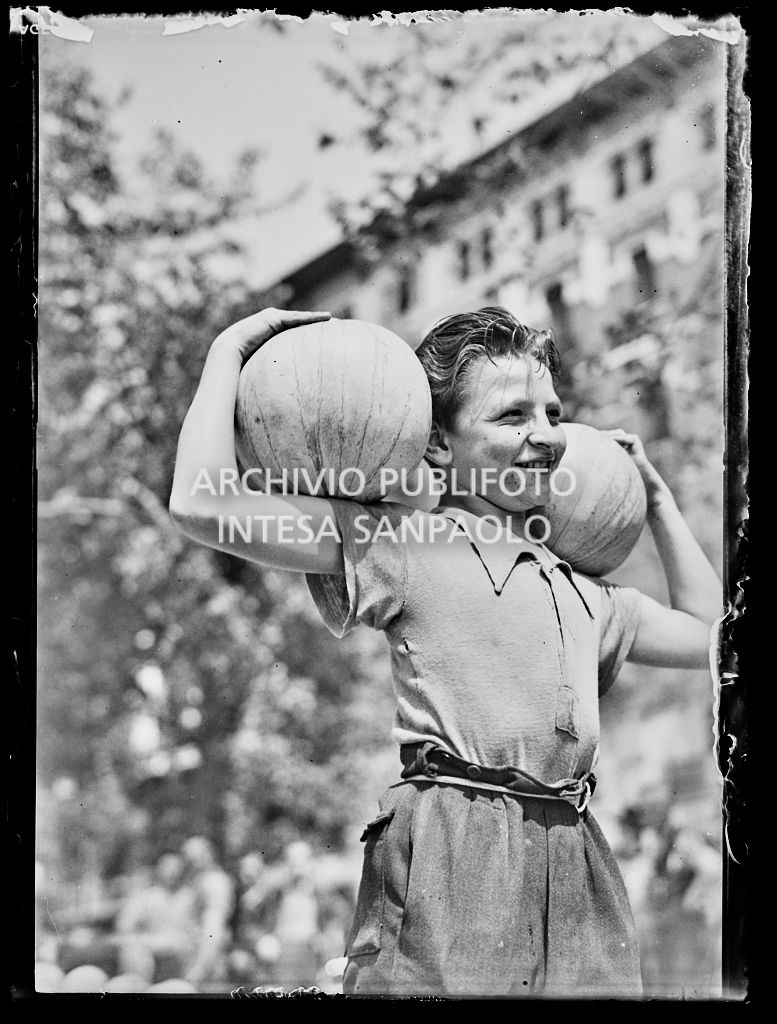 Un ragazzo ritratto con due angurie sulle spalle