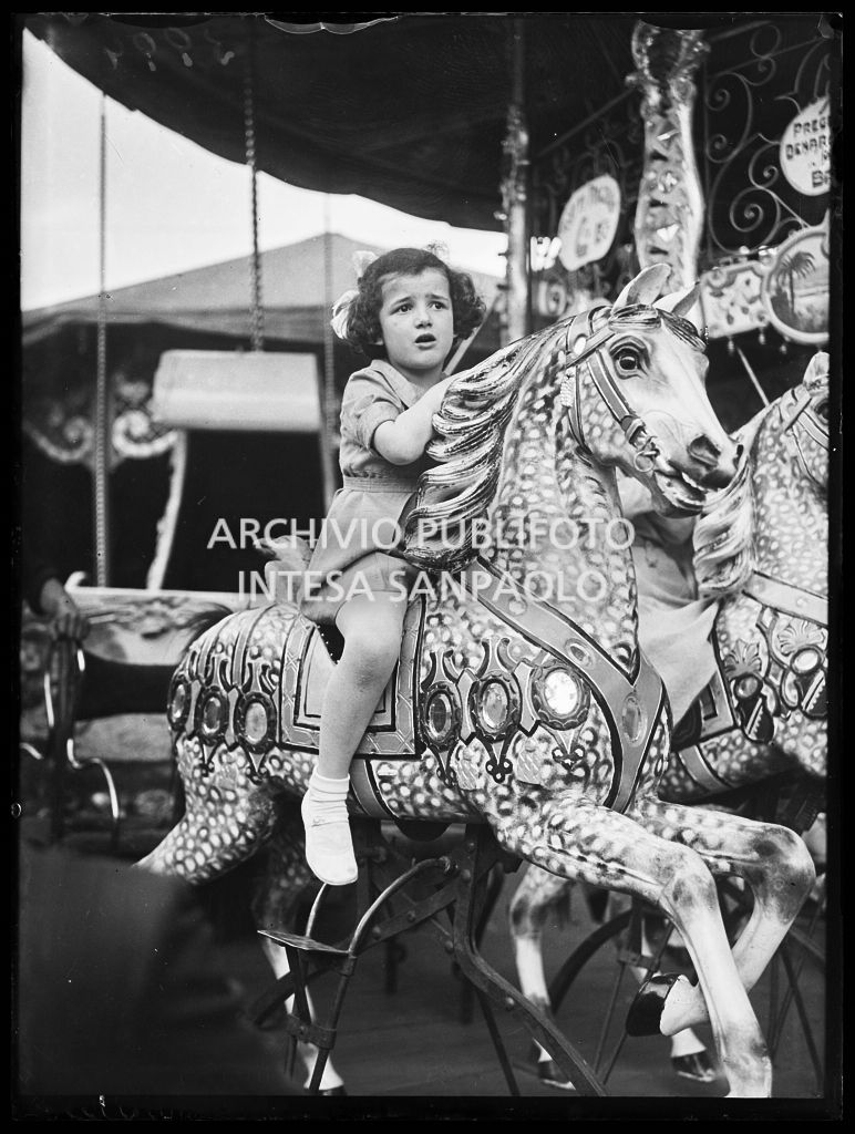 Una bambina su un cavallo di legno di una giostra