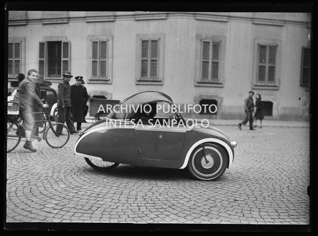 Ciclo vettura, o motociclo carrozzato da vettura, di produzione artigianale, in servizio come auto pubblica, a Milano. Sono visibili le fasce bianche per aumentarne la visibilità durante l'oscuramento