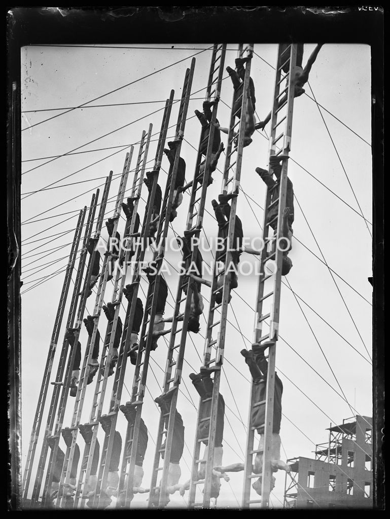 Pompieri in posa acrobatica, su scale a pioli, durante un'esercitazione