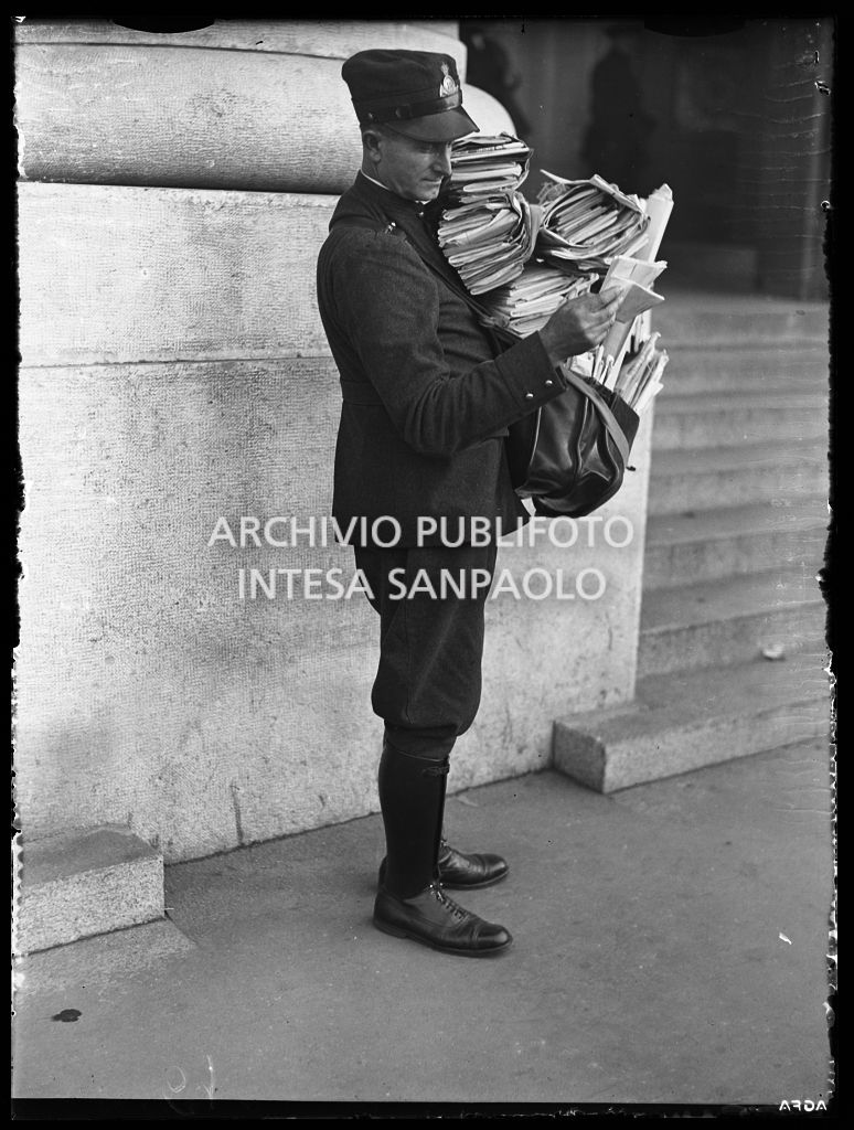 Un postino in divisa con, a tracolla, la borsa straripante di corrispondenza
