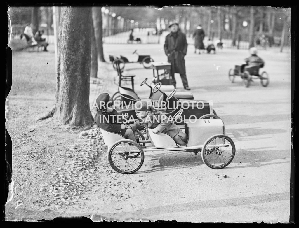Due bambini su un'automobilina a pedali in un parco