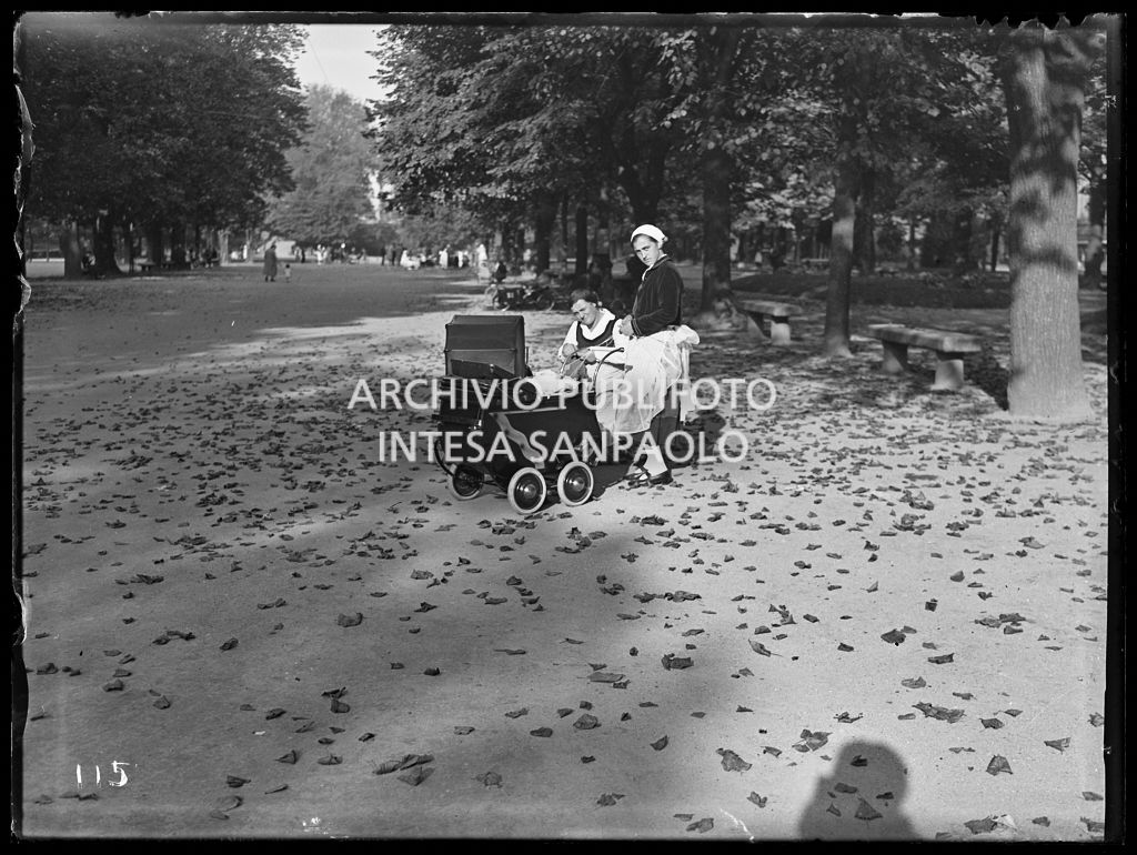 Due bambinaie con carrozzine sedute su una panchina ai Giardini Pubblici di Milano