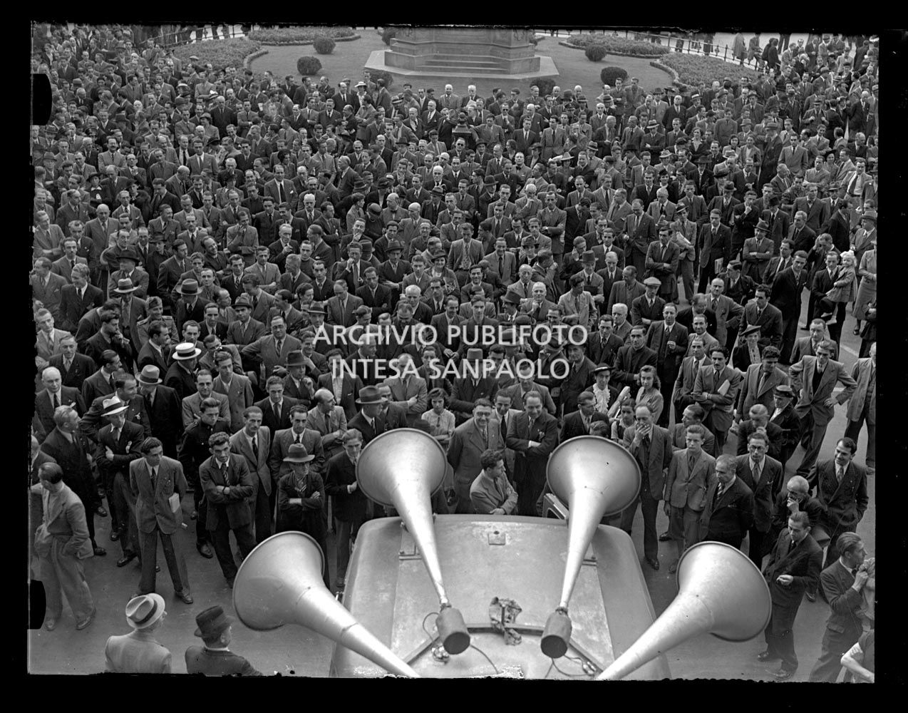 Folla, in piazza della Scala a Milano, ascolta un discorso diffuso dagli altoparlanti posizionati su un furgone