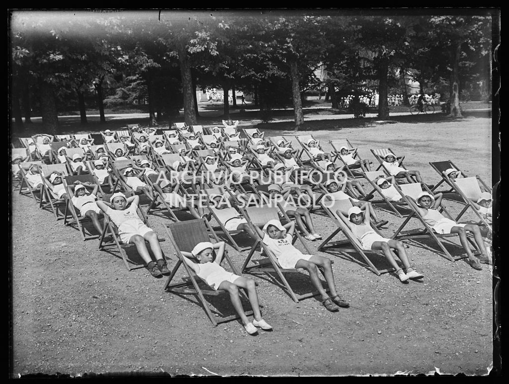 Bambini seduti sulle sdraio al sole in una colonia elioterapica
